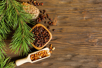 Pine nuts and pine cone on wooden background, place for text