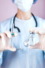 Fototapeta premium Doctor or nurse in medical mask and in protective gloves holds syringe and medical injection in hands. Influenza and coronavirus vaccination. Close-up.