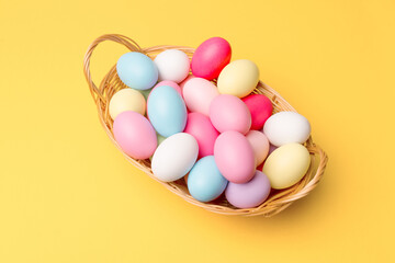 Photo of colorful easter eggs in basket over yellow background