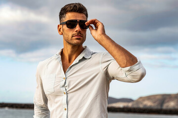 Gorgeous stylish man wearing fashionable shirt and sunglasses. City style. - 417861660