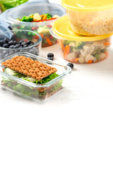 Various food in plastic and glass containers. Salad, bulgur, sandwiches and berries in plastic containers on a white background. Food storage, takeaway. Copy space for text.