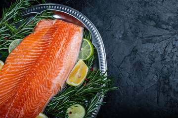 Salmon fillet with lemon and rosemary on a dark background. Top view.