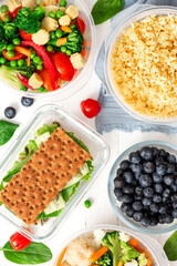 Various food in plastic and glass containers. Salad, bulgur, sandwiches and berries in plastic containers on a white background. Top view. Food storage, takeaway