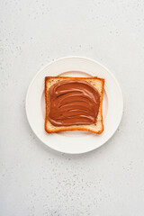 Fresh toast with chocolate paste on a white plate on gray background. View from above.