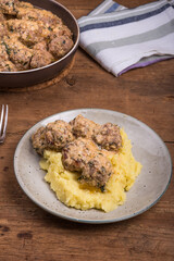 Swedish chicken meatballs with cheese in a creamy sauce with mashed potatoes in a plate on a wooden table, close-up, top view