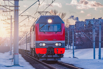 Obraz premium Passenger train moves from the station at sunset winter.