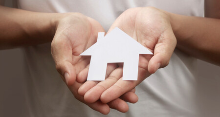 Hands holding paper house, family home  protecting insurance concept