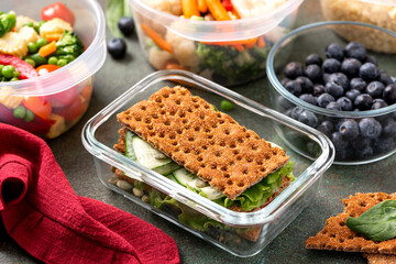 Various food in plastic and glass containers. Salad, bulgur, sandwiches and berries in plastic containers on a dark background. Food storage, takeaway