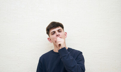 portrait of young tired man who yawns while covering his mouth with his hand