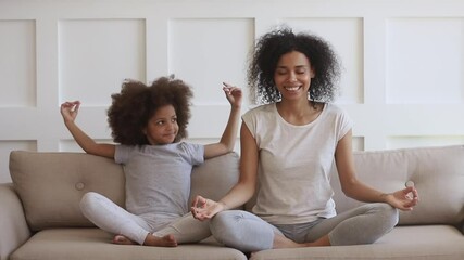 African mom teacFunny african family young healthy mom teaching cute little kid daughter meditate together sit on sofa at home, calm mindful black mother and child girl do yoga exercise relax together - Powered by Adobe