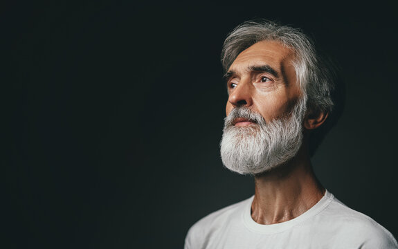 Close up studio portrait of handsome senior man with gray beard.