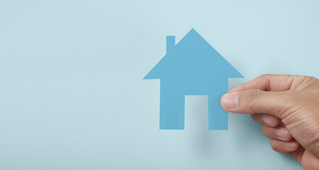 Hands holding paper house, family home  protecting insurance concept