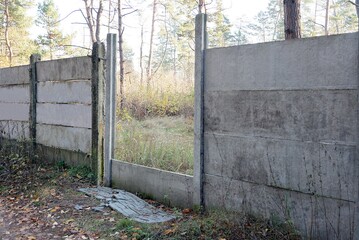 part of a large old concrete gray fence wall with a large hole in the street entrance