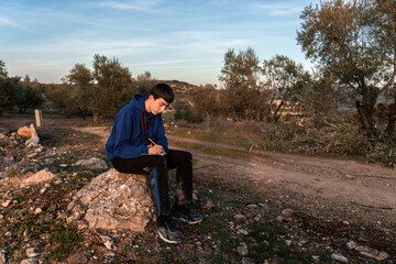 Young boy writing in little notebook while sitting in the countryside.