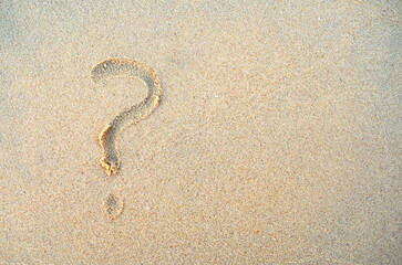 Fototapeta na wymiar Question mark on beach sand with copy space. Question sign is written on a sand.