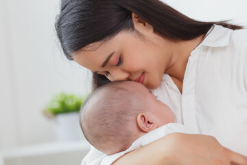 Close up portrait of young beauty Asian mother kissing her newborn baby boy while he sleep. Healthcare and medical insurance. Asia mother's day concept banner.
