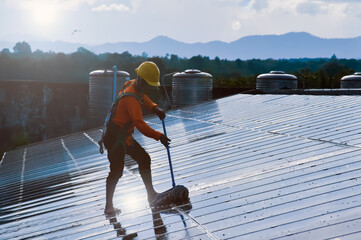 Technician is using a mop and water to clean the solar panels that are dirty with dust and birds' droppings to improve the efficiency of solar energy storage even better. Soft and selective focus.