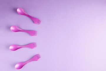 Four plastic purple forks isolated on purple background with copy space.