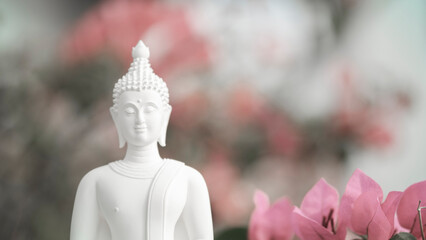 White Buddha statue meditating among nature background and bougainvillea flower