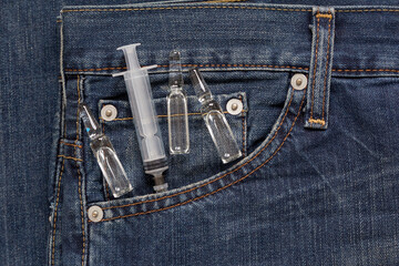 Injection syringe with ampullas are lying in side pocket of jeans. Medical health or drugs...