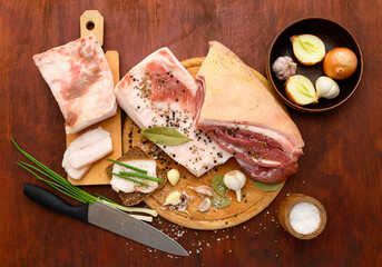 raw pork meat and lard with salt, spices and garlic on a cutting board, dark wooden background