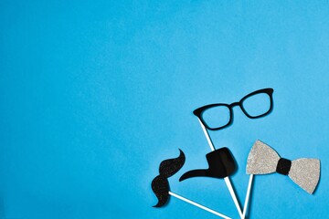 Creative top view of a composition of stylish black mustache, bow tie and eyeglasses on a blue background. Copy space. Men Health Awareness Month. Father's day. masculinity concept.