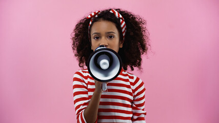 curly african american girl speaking in megaphone isolated on pink