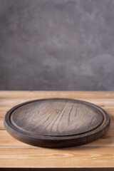 Pizza or bread cutting board for homemade baking on wooden table near grey wall. Front view