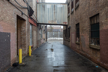 Looking between two vintage industrial brick warehouse buildings with tin metal walkway connection on wet day in urban Chicago - 417874072