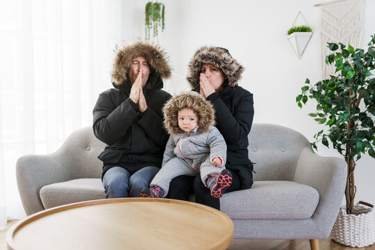 Couple have cold on the sofa at home with winter coat with baby