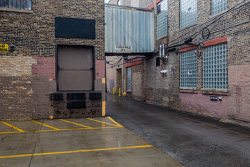 Tin metal passageway between two vintage industrial brick warehouse buildings on wet day in urban Chicago - 417874240