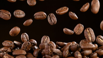 Falling Roasted Coffee Beans on Black Background, close-up.