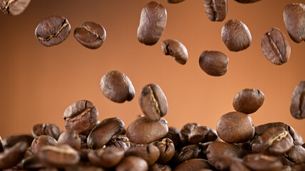 Falling Roasted Coffee Beans on Brown Background, close-up.