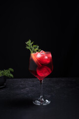 Cóctel rojo en vidrio decorado con rama de eneldo sobre fondo negro