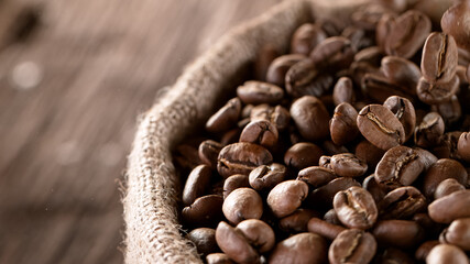 Falling Roasted Coffee Beans into Jute Bag, close-up.
