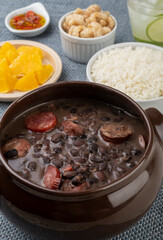 Traditional brazilian feijoada with rice, orange, cracklings, pepper and caipirinha