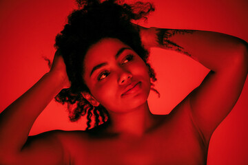 Dancing. Beautiful african-american woman's portrait isolated on red studio background in neon, monochrome. Concept of human emotions, facial expression, sales, ad, fashion and beauty.