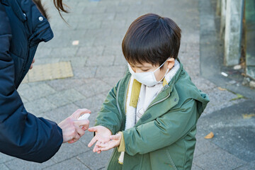 外出先でスプレーで消毒される子供 © maru54