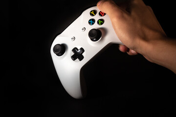 Man holding video game control with black background. Banner for video games and games with space for text. © XM4THX