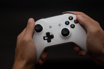 Hands holding video game control against black background