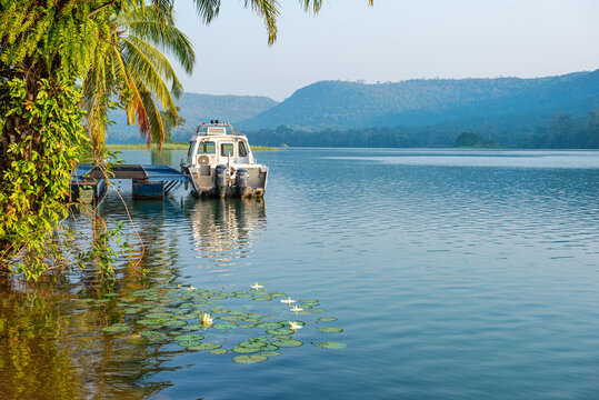 Ravishingly beautiful lake side with blue sky, old boat, and canoe. Coconut tree with men on canoe