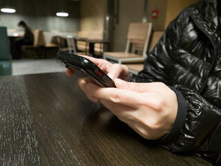 Young casual person holding and using smartphone, text message, typing touchscreen cell phone in the cafe. business, lifestyle, technology and Social media network concept