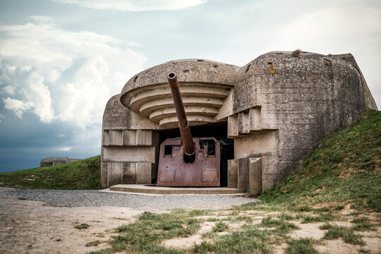 Atlantic wall concrete German World War Two gun emplacement fortification bunker naval battery at Longues-sur-mer in Normandy Gold Beach France remains lay in ruins with dramatic cloudy storm sky