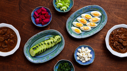 Bowls and plates with different breakfast meal ingredients. Flat lay table view with ful medames...