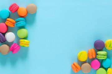 Cake macaron or macaroon on turquoise pastel background from above. Colorful almond cookies on dessert top view.