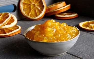 Orange marmalade in bowl. Portion of orange fruit jam with dried orange slices.