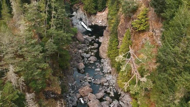 Upward panning drone shot of a beautiful valley with a small river flowing through with a waterfall in the distance located in rural British Colombia, Canada.