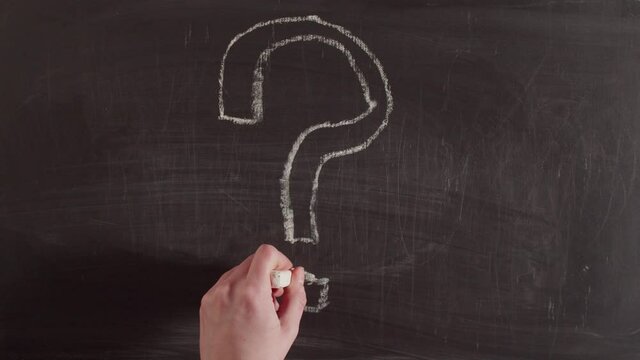 Timelapse write a question mark on a chalkboard. The question mark is drawn with chalk in hand close-up on the blackboard. Answer search concept.