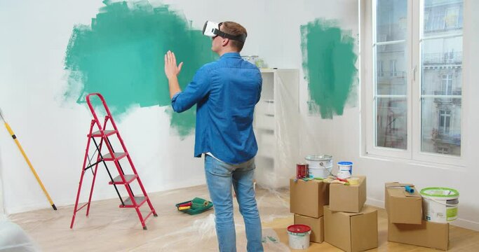 Caucasian man in VR glasses creating home design moving hands in air standing in new house during renovation, virtual reality, futuristic technology, repair concept