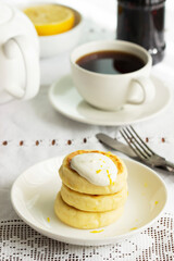 Cottage cheese pancakes with sour cream and lemon zest, served with tea.